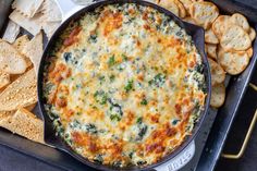 a casserole with spinach and cheese in a pan next to crackers