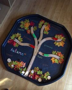 a child's toy train set sitting on top of a wooden floor next to an autumn themed tray