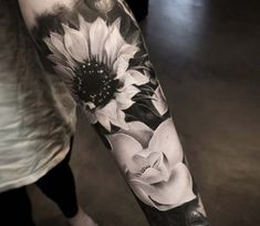 a person with a sunflower tattoo on their arm and leg, in black and white