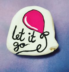 a white rock with the words let it go written on it and a pink hat