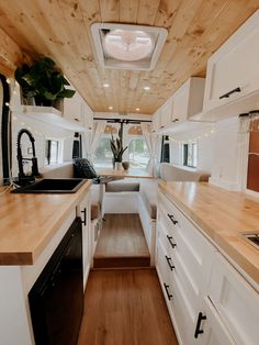 the interior of a camper with wood flooring and white cabinets, counter tops and drawers