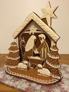 a nativity scene made out of gingerbread and decorated with white icing on a wooden table