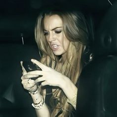 a woman sitting in the back seat of a car looking at her cell phone