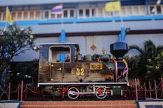 an old train on display in front of a building with flags hanging from it's sides