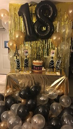 a table topped with black and gold balloons