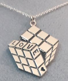 Are you looking for a very special gift? How about this gorgeous sterling silver pendant necklace with the famous Rubik's Cube? The architect and designer responsible for the cube, Erno Rubik, took about a month to figure out his own creation. In fact, he was so desperate that he even wondered if his new puzzle had a solution. The funny thing is that he created it as a math problem. Come on, it came out almost by chance. All the pieces can be personalized (engrave names, initials, dates on the b Math Problem, New Puzzle, Pendant Necklace Silver, Rubik's Cube, Dragonfly Pendant, The Architect, The Funny, Sterling Silver Necklace Pendants, Silver Pendant Necklace