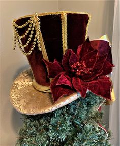 a red hat sitting on top of a christmas tree with a poinsettia