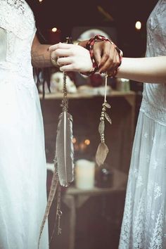 two women wearing bracelets with feathers attached to them