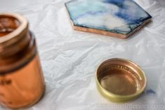 an empty glass jar sitting on top of a table next to a small gold container