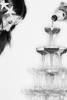 a woman standing next to a wine rack filled with champagne flutes and star shaped glasses