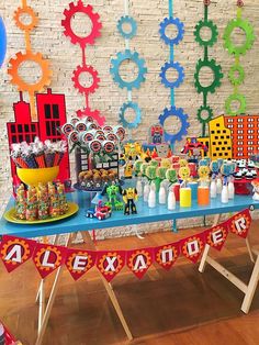 a table topped with lots of candy and decorations next to a wall covered in gears