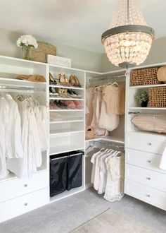 an organized closet with clothes, shoes and other items on shelves under a chandelier