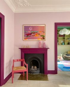 a living room with a fire place and pink paint on the walls, along with a chair