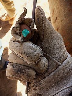 a gloved hand holding a green object in it's right hand, with other people standing around