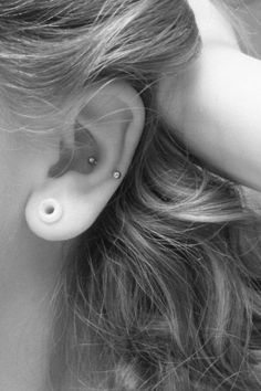 black and white photograph of a woman's ear with an in - ear piercing