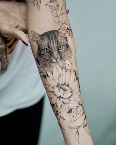 a woman's arm with a cat and flowers tattoo on the left side of her arm