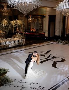 a bride and groom kissing on the dance floor at their wedding reception in an elegant ballroom