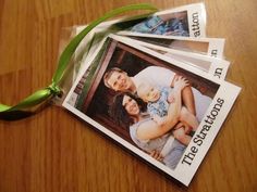 three photos are wrapped in plastic and tied with a green ribbon on a wooden table