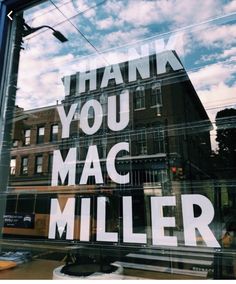 the reflection of a building in a glass window that says, thank you mac miller