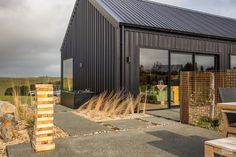 a black building sitting on top of a grass covered field next to a wooden bench