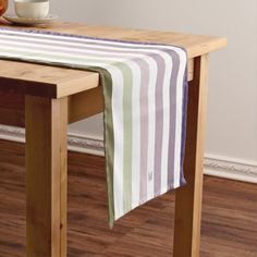 a table with a striped cloth on it next to a bowl of oranges and an apple