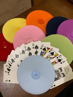 several different colored playing cards sitting on top of a wooden table next to each other