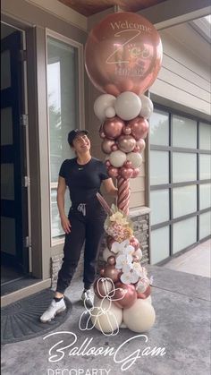 a woman standing in front of a balloon column with balloons attached to the top and bottom