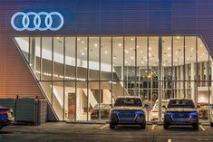 three cars are parked in front of an audi dealership at night with the lights on