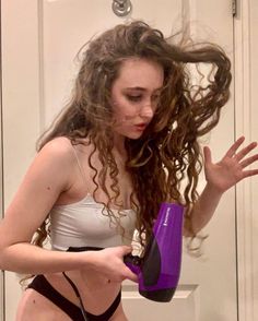 a woman is drying her hair with a blow dryer in front of the door