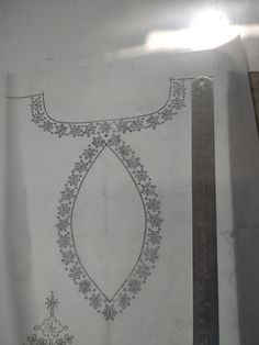 a piece of paper with an embroidered design on it and a ruler next to it