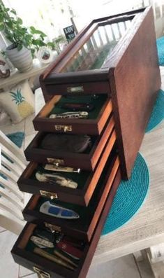 an open drawer on top of a table with glasses and other items in the drawers