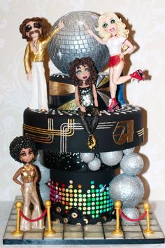 there are many figurines on top of a cake that is decorated with disco balls