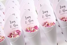 there are many white paper cones with pink flowers in them that say, lucy & ben