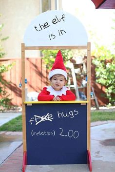 a child dressed as an elf in front of a sign