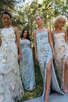 four women in long dresses walking on the grass with one woman wearing high heeled sandals