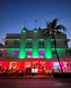 a large white building with green and red lights on it's sides at night