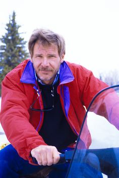 a man sitting on the hood of a car with his hand on the door handle