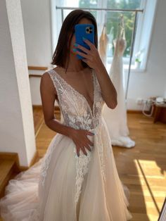 a woman taking a selfie while wearing a wedding dress and holding a cell phone