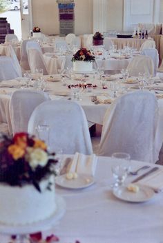 there are many tables with white linens and flowers on the tablecloths, but no one is in it