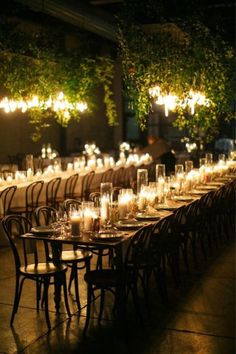 a long table is set with candles and wine glasses for an elegant dinner or party