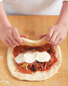 a person is kneading cheese on top of a pizza doughnut with tomato sauce and onions