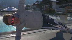 a man doing a handstand in front of a swimming pool with snow on the ground