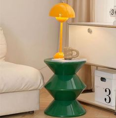 a green lamp sitting on top of a table next to a white chair