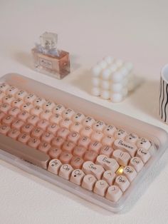 a pink keyboard sitting on top of a table next to a coffee cup and candle