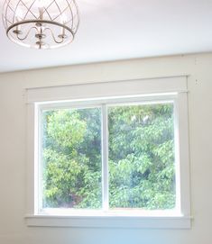 a bedroom with a bed and a large window in the corner that has trees outside