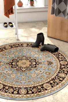 a pair of black high heeled shoes sitting on top of a blue and beige rug