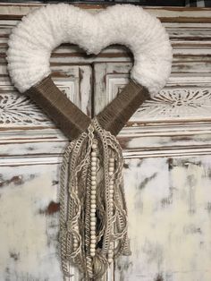 a heart shaped wreath hanging on the side of a wooden door with white and brown trim