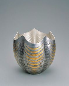 a silver and gold vase sitting on top of a table