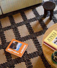 two books are sitting on the floor next to a coffee table with an orange book