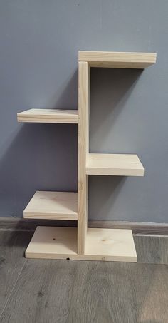 a wooden shelf sitting on top of a hard wood floor next to a gray wall